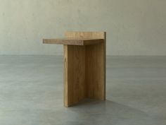 a small wooden object sitting on top of a cement floor in front of a wall