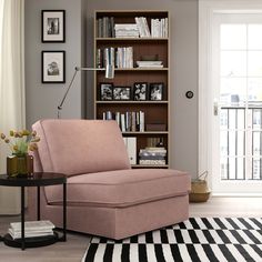 a living room with a gray chair and bookshelf in the corner, next to a black and white striped rug