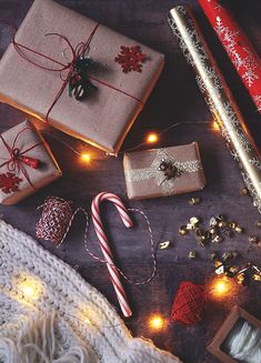 christmas presents are laid out on a wooden table with lights and candy canes next to them