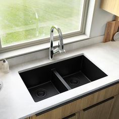 a kitchen sink sitting under a window next to a counter