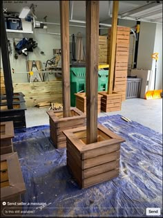 two wooden planters sitting on top of a blue tarp in a room filled with wood