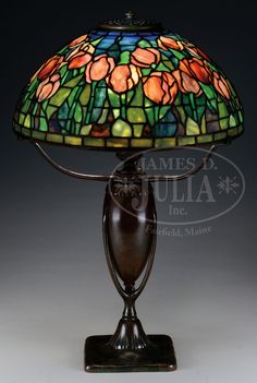 a stained glass lamp on a stand with a brown base and flower pattern in the shade