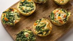 mini quiches filled with spinach and cheese on a wooden cutting board, ready to be eaten