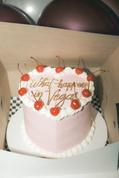 a pink birthday cake with cherries in a box