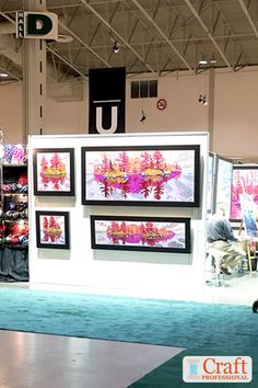 a man is standing in front of some art on display at a convention or exhibition