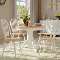 a dining room table with four chairs and a clock hanging on the wall above it