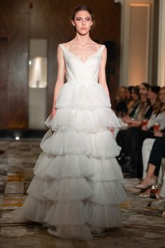 a woman in a white wedding dress walking down the runway at a fashion week event