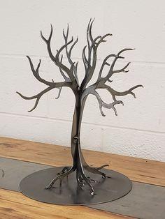 a metal tree sculpture sitting on top of a wooden table next to a white wall