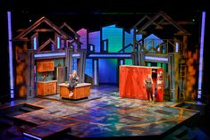 the stage is set for an upcoming play, which features wooden furniture and colorful lighting