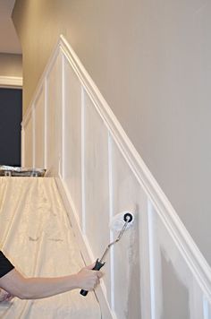 a woman is painting the wall with white paint