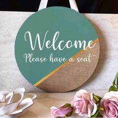 a sign that says, welcome please have a seat next to some pink roses and white flowers