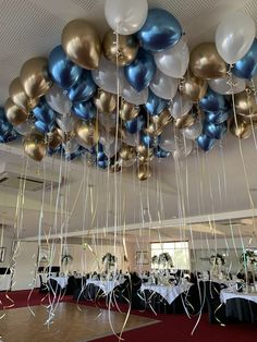 balloons and streamers hanging from the ceiling in a banquet hall with tables set up for an event