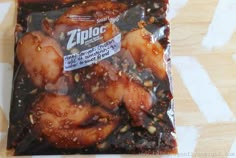 a ziploc bag filled with chicken wings on top of a wooden tablecloth