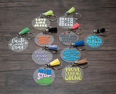 six keychains with different designs on them sitting on a wooden surface, one has the words jesus loves jesus and the other says prove you can't stop