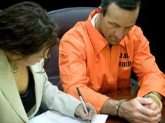 a man and woman sitting at a table signing papers