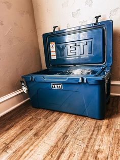 a large blue cooler sitting on top of a hard wood floor next to a wall