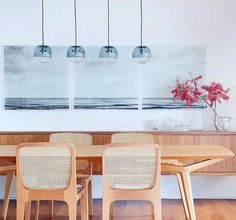 a dining room table with four chairs in front of it and a painting on the wall