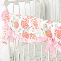 a white crib with pink and blue floral bedding on it's sides