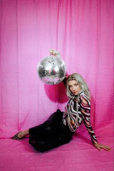 a woman sitting on the ground with a disco ball