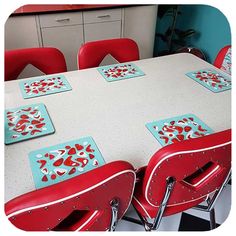 a white table with red chairs and matching placemats is shown in this image