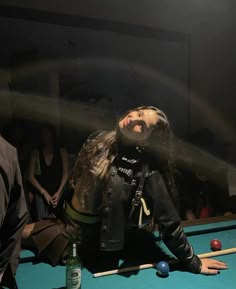 a woman sitting on top of a pool table in front of a pool ball rack