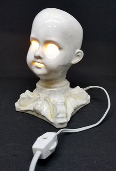 a white plastic head with glowing eyes and an electrical cord plugged in to it