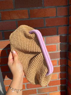 a hand holding a straw hat on top of a brick wall