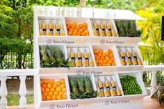 an outdoor fruit stand with oranges and pineapples