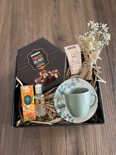 a cup and saucer sitting on top of a wooden table next to a box