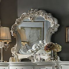 a white dresser with a mirror on top of it next to a lamp and two lamps