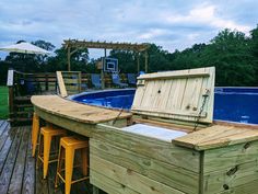 a wooden deck next to a swimming pool with an open trunk on it's side