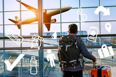 a man standing in front of an airport window with luggage and planes flying above him