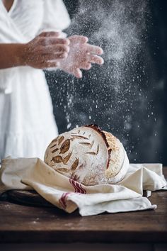 a person sprinkling flour on top of a loaf of bread