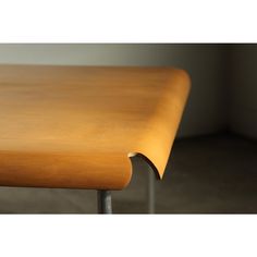 a close up of a wooden table with metal legs and a curved edge on the top