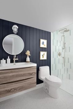 a white toilet sitting next to a walk in shower under a bathroom mirror above a sink