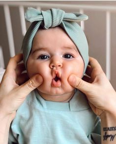 a woman holding a baby in her hands and making a funny face with it's tongue