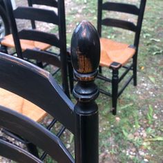 three wooden chairs sitting next to each other in the grass and one chair has been painted black