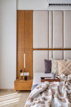 a bed with pillows and blankets on it next to a wooden headboard in a bedroom