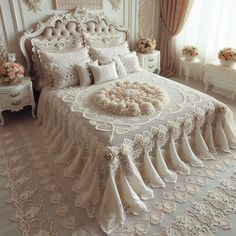 a large white bed sitting in a bedroom next to a window with curtains and flowers on it