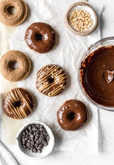 chocolate donuts and other desserts are on the table with white paper, including peanut butter