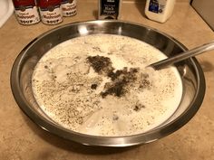 a bowl filled with liquid and spices on top of a counter next to bottles of milk