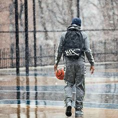 a man walking in the rain with a basketball