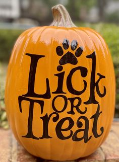 a pumpkin with the words lick or treat written on it and a paw print in black ink