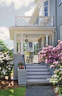 a house with flowers in the front yard and stairs leading up to the second story