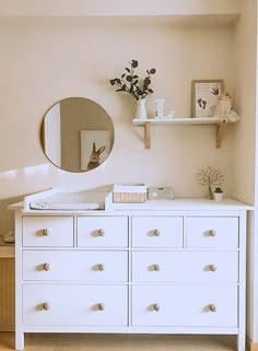 a white dresser with drawers and a mirror on the wall above it in a bedroom