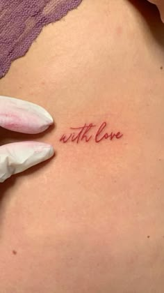 a woman's stomach with the word love written on it and a glove holding up her arm