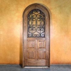 an old wooden door with iron work on the top and bottom part, in front of a yellow wall