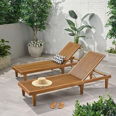 two wooden lounge chairs sitting next to each other on top of a cement floor covered patio