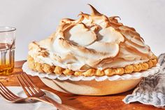 a pie sitting on top of a wooden table next to a fork and glass filled with liquid