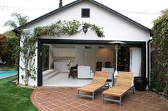 an open garage door with two lounge chairs in front of it and a swimming pool